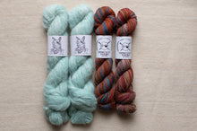 Load image into Gallery viewer, Two skeins of light blue yarn and two skeins of multicolored yarn on a beige surface with &#39;Spin Cycle Yarns&#39; labels.