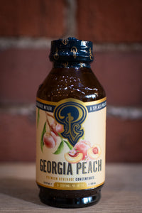 Georgia Peach beverage concentrate bottle with blue cap on a wooden surface