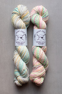 Two skeins of multicolored yarn with labels on a gray background