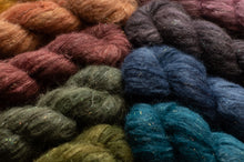 Load image into Gallery viewer, Close-up of several twisted skeins of fuzzy yarn in mixed colors, including rust orange, burgundy, charcoal, navy, olive green, and teal, with small sparkly fibers visible throughout.
