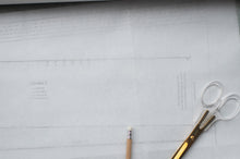 Load image into Gallery viewer, Scissors and a pencil on a piece of paper with grid lines