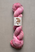 Load image into Gallery viewer, Pink skein of yarn with a label on a gray background