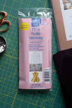 Load image into Gallery viewer, Package of Pellon fusible interfacing on a cutting mat with scissors and fabric.