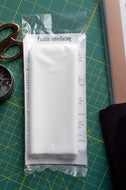 Packaged fusible interfacing on a cutting mat with scissors and fabric.