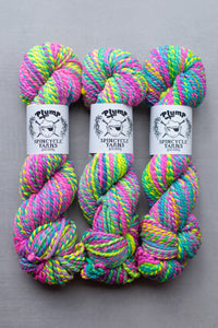 Three skeins of colorful yarn with 'Plump Spindycle Yarns' labels on a gray background