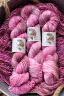 Three skeins of pink yarn with 'Fox Lady' labels in a basket.