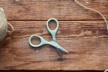 Load image into Gallery viewer, Pair of green scissors on a wooden surface with string