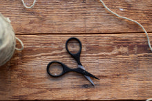 Load image into Gallery viewer, Black scissors on a wooden surface with twine