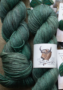 Green yarn skeins with a label on a brown surface