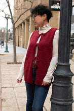 Load image into Gallery viewer, Woman wearing a red vest over a white shirt on a city street.