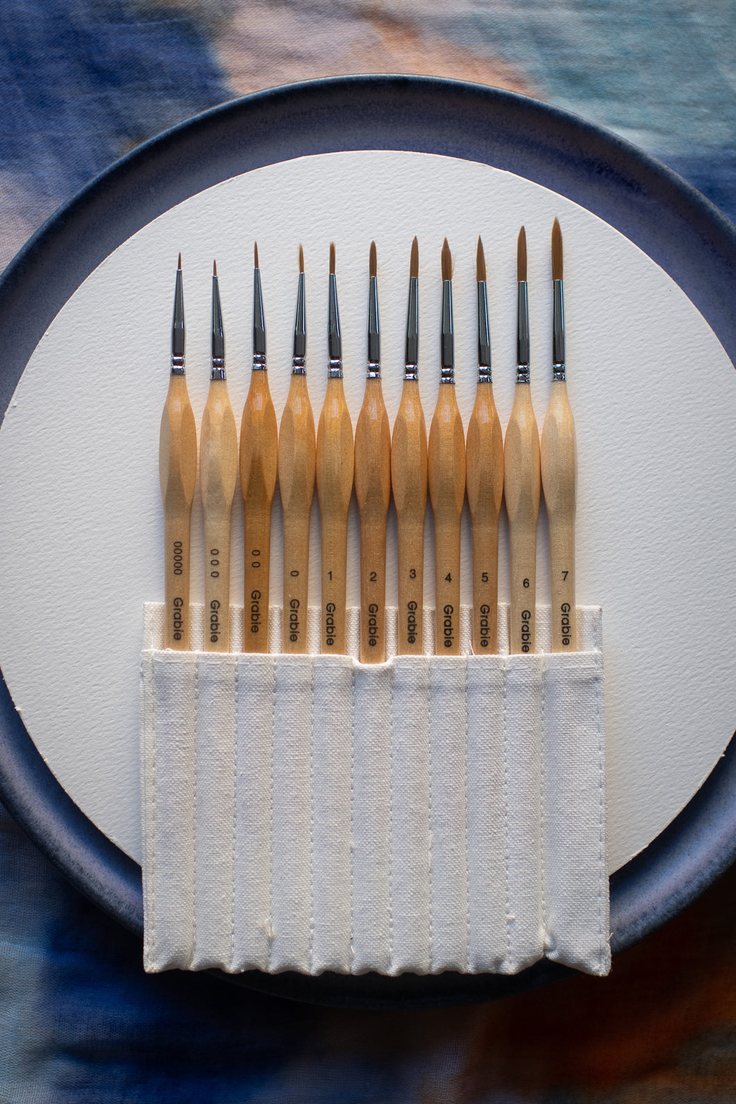 Set of wooden paintbrushes in a white holder on a blue and gray background