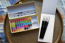 Load image into Gallery viewer, Art supply set with watercolor paints and brushes on a wooden tray.