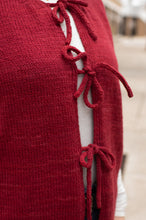 Load image into Gallery viewer, Red knitted cardigan with tie details on a blurred background