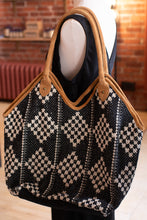 Load image into Gallery viewer, Black and white patterned handbag with brown leather trim on a mannequin against a brick wall.
