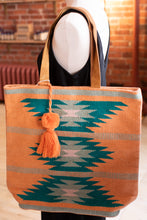 Load image into Gallery viewer, Tote bag with geometric pattern and tassel on a mannequin against a brick wall.