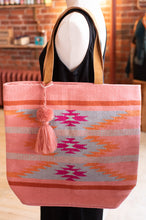 Load image into Gallery viewer, Mannequin holding a pink tote bag with geometric patterns and a tassel.