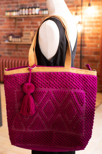 Mannequin wearing a pink textured handbag with a tassel in a store setting.