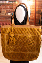 Load image into Gallery viewer, Brown knitted tote bag with a tassel on a mannequin against a brick wall background