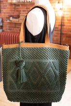 Load image into Gallery viewer, Green woven tote bag with brown leather handles on a mannequin against a blurred indoor background.