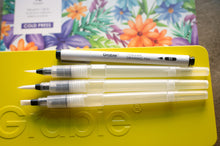 Load image into Gallery viewer, Three drawing pens on a yellow holder with a floral painting in the background