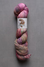 Load image into Gallery viewer, Multicolored skein of yarn with a label on a gray background