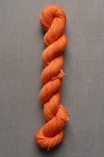 Load image into Gallery viewer, Orange skein of yarn on a gray background