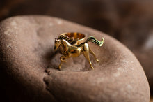 Load image into Gallery viewer, Gold horse-shaped ring on a stone surface