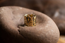 Load image into Gallery viewer, Gold ring with intricate design on a textured stone surface