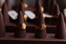 Load image into Gallery viewer, Two gold rings on brown cone-shaped stands with a blurred background