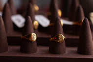 Two gold rings on brown cone-shaped stands with a blurred background