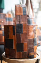 Load image into Gallery viewer, Patchwork leather bag on a wooden stand with blurred background