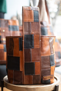 Patchwork leather bag on a wooden stand with blurred background
