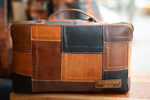 Patchwork leather bag with 'Redesigned Project' label on a wooden surface.