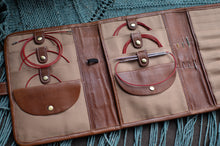 Load image into Gallery viewer, Brown leather wallet with intricate designs on a textured fabric background