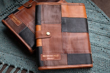 Load image into Gallery viewer, Brown leather patchwork wallet with &#39;Redesigned Project&#39; branding on a textured surface.