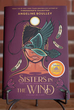 Load image into Gallery viewer, Book cover of &#39;Sisters in the Wind&#39; by Angeline Boulley on a stand with a blurred background.