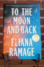 Load image into Gallery viewer, Book titled &#39;To the Moon and Back&#39; by Eliana Ramage on a stand with a blurred background.