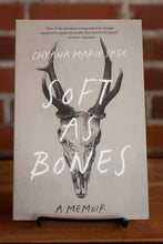 Load image into Gallery viewer, Book titled &#39;Soft as Bones&#39; by Chyana Marie Sage on a stand with a blurred background