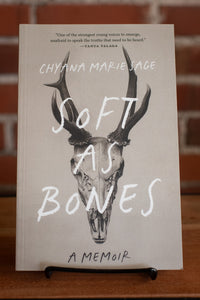 Book titled 'Soft as Bones' by Chyana Marie Sage on a stand with a blurred background