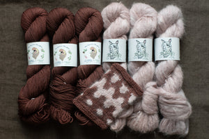 Three skeins of brown yarn and three skeins of pink yarn with matching knitted fabric on a dark background.
