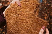 Load image into Gallery viewer, Brown textured fabric held by hands with a blurred autumn background