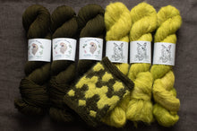 Load image into Gallery viewer, Three skeins of green yarn and two skeins of yellow yarn with matching knitted fabric on a dark background.