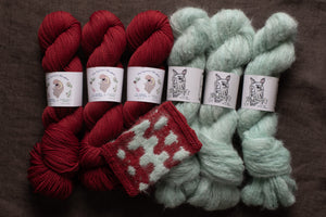 Red and green yarn skeins with matching knitted swatches on a brown background