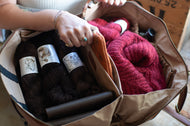 Person organizing yarn balls and books in a bag