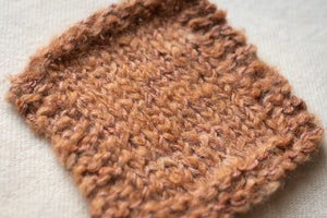 Close-up of a brown knitted fabric swatch on a light background