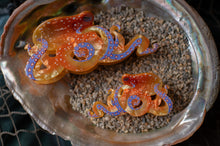 Load image into Gallery viewer, Decorative orange and purple octopus figurines on a bed of sand inside an oyster shell.