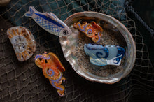 Load image into Gallery viewer, Decorative fish figurines inside a shell on a textured surface