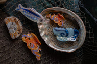 Decorative fish figurines inside a shell on a textured surface