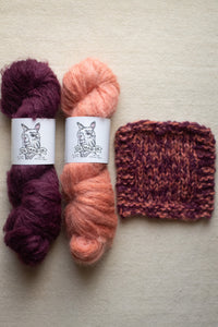 Two skeins of yarn in purple and pink with a knitted swatch on a beige background