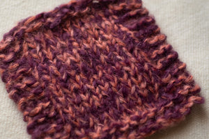 Close-up of a knitted fabric with a textured pattern on a neutral background